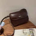 Dunkelbraune Vintage Leder Umhängetasche mit Metallverschluss und Kontrastnähten Detail. - Weinpurpur