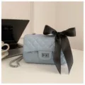 Chic light blue quilted chain shoulder bag with black bow, stylish crossbody design. - Blue
