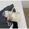 Stylish white pebbled leather crossbody bag with cute bear charm and top handles for women. - With Pendant / White