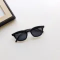 Detailed view of children's black fashion sunglasses with metal rivets on the square frame. - Black