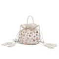 Primer plano de un bolso tipo cubo blanco con asa de perlas, pedrería colorida y borlas finas. - Blanco