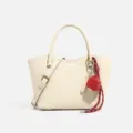 Bolso cruzado de cuero texturizado blanco crema con bonito colgante de fresa y correa ajustable. - Blanco