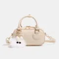 Elegante bolso cruzado beige efecto cocodrilo con un tierno colgante y detalles dorados. - Blanco