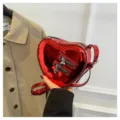 Sac bandoulière en cuir verni rouge en forme de cœur avec doubles fermetures et pendentifs. - Rouge