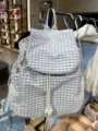 Detailed close-up view of casual plaid backpack featuring drawstring and flap design. - White Plaid