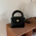 Black leather handbag with gold heart lock on wooden table, detailed view of textured bag. - 20*8*14cm / Black Handbag
