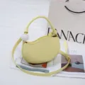 Stylish yellow crescent pea shoulder bag with unique white ball handle accessory for women. - Light Yellow