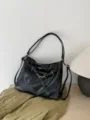 Detail view of black soft leather hobo tote bag with metal buckle and shoulder strap. - Black