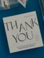Gros plan d'une carte de remerciement carrée avec élégante typographie noire sur papier. - Carte Thank You Carrée / 50 Pièces