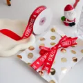 Vista detallada de cinta navideña roja con texto blanco y bonito diseño de árbol. - Ancho Aprox 2cm / Rojo