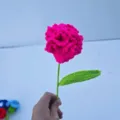Gedetailleerde close-up van handgemaakte gehaakte anjerbloem met groene stengel. - Roze