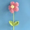 Close-up detail van handgemaakte gehaakte bloem met roze bloemblaadjes en bladeren, garen. - Mode Roze