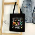 Vista detallada de un bolso de lona negro con estampado musical colorido y asas muy resistentes. - Estilo Eslógan Música 19