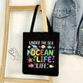 Vista detallada del bolso de lona negro con estampado marino colgado en escalera de madera. - Estilo Tema Océano 17