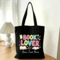 Vista dettagliata della borsa in tela nera con stampa tema libri e testo personalizzabile. - Amante dei Libri Libri a Cartoni Animati (07)