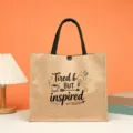 Jute tote bag with creative printed slogan and black handles for daily shopping use. - Tired but inspired