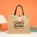 Detailed view of jute tote bag featuring teacher print, black handles and natural linen fabric. - Style 5