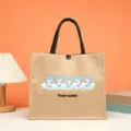Close-up detail of custom jute tote bag featuring cute cartoon dolphins and personalized name. - Style 7