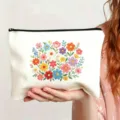 Nahaufnahme einer weißen Kosmetiktasche aus Canvas mit farbiger Blumenstickerei und Reißverschluss. - Stil 20