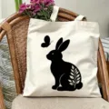 Vista dettagliata della borsa di tela bianca con stampa di coniglio e farfalla nera. - Stile 04