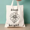 Nahaufnahme einer cremefarbenen Stofftasche mit schwarzem Blumenmuster und Aufdruck. - Linien-Blumen-Stil (17)