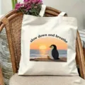Detailed view of the canvas tote bag featuring a cute penguin and sunset beach graphic. - Penguin Style (10)