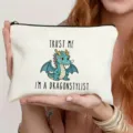 Detail view of white canvas cosmetic pouch with cute dragon print and zipper closure. - Dragon Stylist