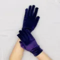 Detail view of dark purple velvet short gloves, elastic fabric, ideal for party wear. - Violet