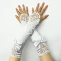 Detailaufnahme von weißen Brautspitzenhandschuhen mit filigraner Stickerei und Satinmasche. - Weiß