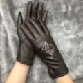 Close-up detail of women's brown leather touch screen gloves with cute embroidered pattern. - One Size / Brown