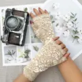 Close-up detail of women's beige floral lace fingerless sun protection gloves texture. - One Size / Beige