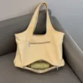 Detail van de shopper met handig onderste vak met rits voor het opbergen van paraplu. - Geel