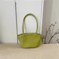 Vista dettagliata della borsa tote in pelle intrecciata con classico design e manici. - Verde