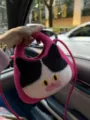 Dettaglio della borsa a tracolla in feltro con viso di gatto e morbido cinturino rosa chiaro. - Rosso rosa