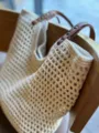 Close-up detail of beige crochet mesh tote bag with brown leather handles hanging on a chair. - Zipper Style / L / Off White