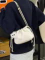 Vue détaillée du sac seau à cordon froissé blanc avec bandoulière chaîne et breloque en peluche. - Blanc