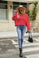 Detailed view of the women's casual loose cropped crewneck sweater styled in a chic street scene. - Watermelon red