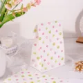 Vista detallada de bolsas de papel de lunares con patrones rosas y verdes para regalos. - Puntos de Colores