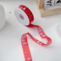 Close-up of red organza Christmas ribbon with gold stars and white trees for holiday gift wrapping. - One Roll 25 Yards Price / Red