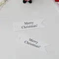 Close up detail of white paper Christmas swallowtail hanging tags with Merry Christmas text. - White English Text