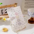 Vue détaillée du sac en papier à pois mignons avec expressions colorées dans le panier. - Style Emoji / 14x24cm