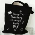 Detailed view of a black canvas tote bag featuring teacher quotes and cute educational icons. - Style 6