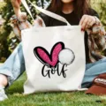 Detailansicht der lässigen weißen Segeltuchtasche mit niedlichem rosa Herz- und Golf-Grafikdesign. - Golf-Druck / 35x40cm