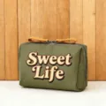 Detailansicht der olivgrünen Kosmetiktasche mit Sweet Life Druck und Lederschiebern. - Sweet Life Stil
