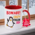 Detailansicht der weißen Keramiktasse mit rotem Henkel und niedlichem Pinguin Druck für Weihnachten. - Rot Pinguin Stil