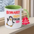 Detailansicht einer Keramiktasse mit Pinguin Motiv und Weihnachtsetikett am Fenster. - Grün Pinguin Stil