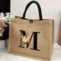 Detailed view of the jute tote bag featuring letter M and floral print with black handles. - Floral Alphabet-M