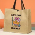 Chic jute tote bag with cute crochet character print, durable black handles for daily fashion use. - Cartoon Character Print Style (3)