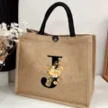 Close-up detail shot of a custom burlap jute tote bag with floral letter J print and handles. - Floral Alphabet-J