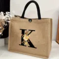 Large capacity jute tote bag featuring stylish floral letter K print for travel and beach. - Floral Alphabet-K